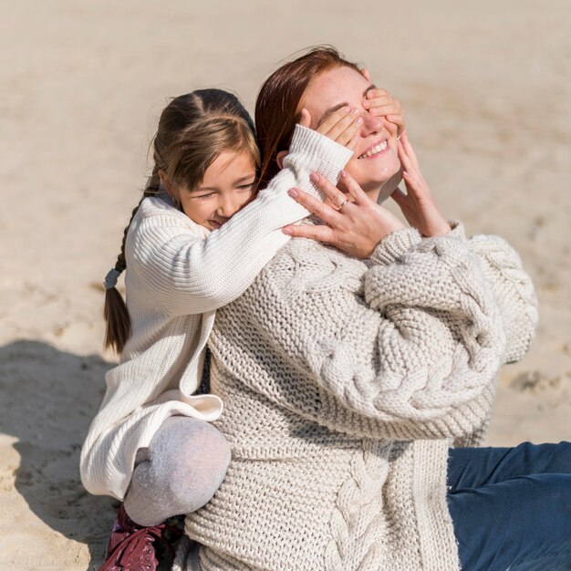 Madre e ragazza del colpo medio in spiaggia