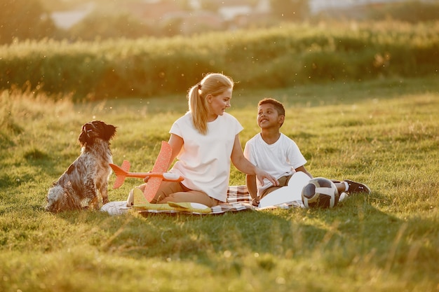 Madre europea e figlio africano. Famiglia in un parco estivo. Persone sedute sulla coperta.