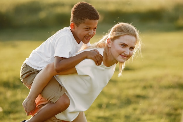 Madre europea e figlio africano. Famiglia in un parco estivo.