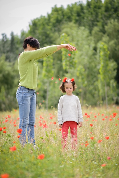 Madre felice con la sua piccola figlia nel campo del papavero