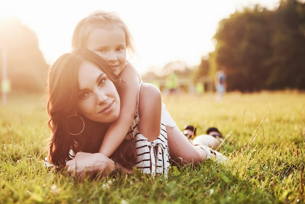 Madre felice e figlia che abbracciano in un parco al sole su un'estate luminosa di erbe.