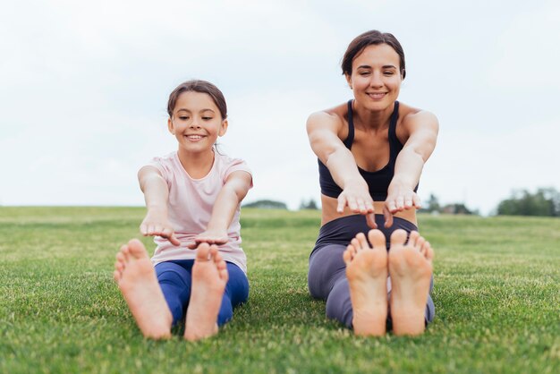 Madre felice e figlia toccando le dita dei piedi in natura