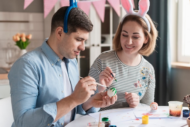 Madre felice e padre che dipingono le uova di Pasqua