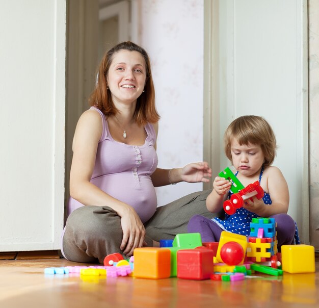 Madre incinta felice gioca con bambino