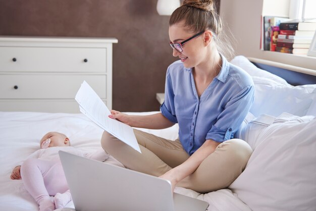 Madre moderna che lavora mentre il suo bambino dorme