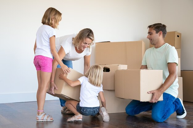Madre, padre e due figlie con scatole di cartone in soggiorno