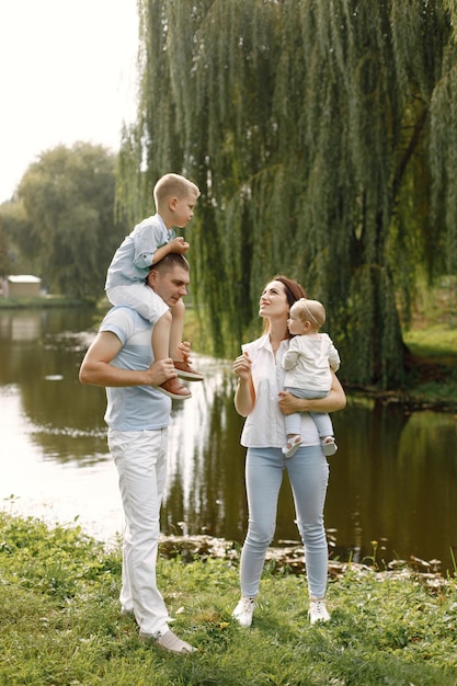 Madre, padre, figlio maggiore e piccola figlia che camminano nel parco. Famiglia vestita di bianco e azzurro