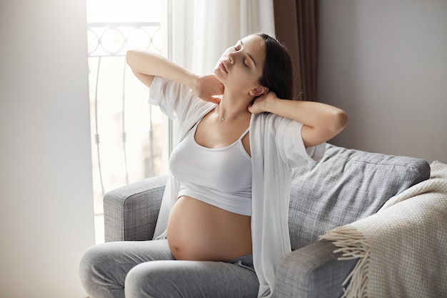 Madre scontrosa stanca della sua gravidanza Mantenersi motivati a stare da sola a casa è difficile Alleviare la tensione al collo e alla schiena