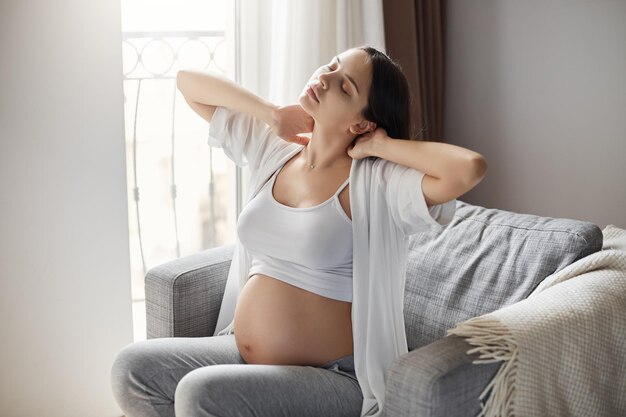 Madre scontrosa stanca della sua gravidanza Mantenersi motivati a stare da sola a casa è difficile Alleviare la tensione al collo e alla schiena