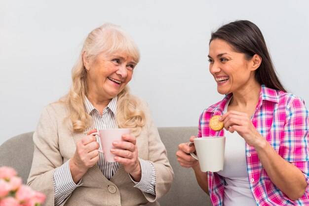 Madre senior sorridente e sua figlia che mangiano prima colazione insieme