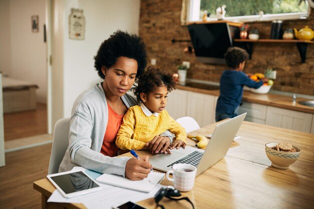 Madre single afroamericana con due bambini che lavorano a casa