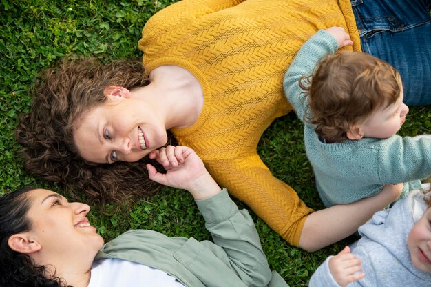 Madri LGBT fuori nel parco con i loro bambini che si rilassano sull'erba