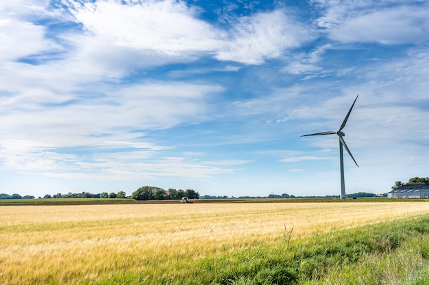 Maestosa vista paesaggistica di un terreno con un mulino a vento per la generazione di elettricità sotto un cielo nuvoloso