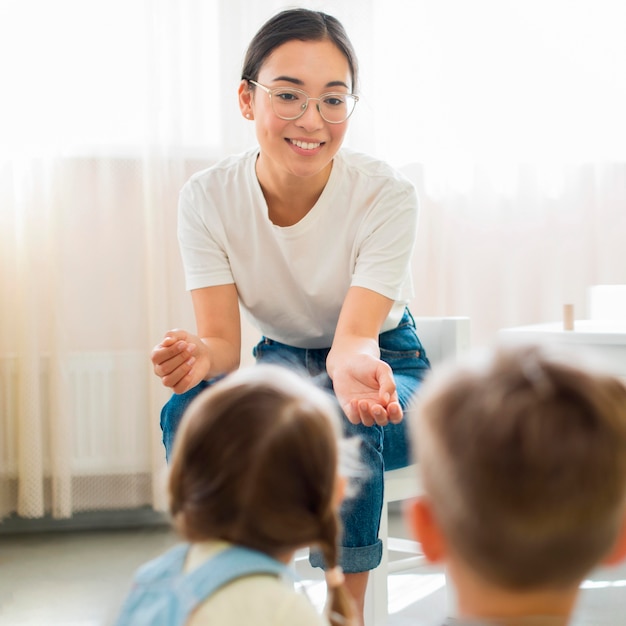 Maestra d'asilo che spiega qualcosa ai suoi studenti