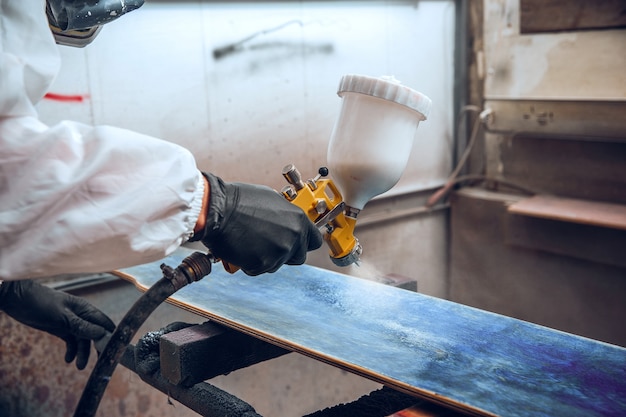 Maestro pittore in una fabbrica - pittura industriale del legno con pistola a spruzzo.