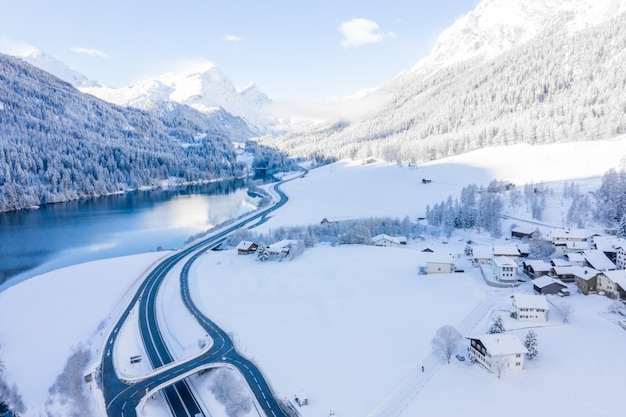 Magico lago invernale svizzero nel centro delle Alpi circondato dalla foresta ricoperta di neve