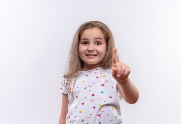 Maglietta bianca da portare della bambina sorridente della scuola che mostra uno su fondo bianco isolato