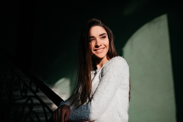 Magnifica ragazza dai capelli lunghi con sorriso ispirato che guarda lontano