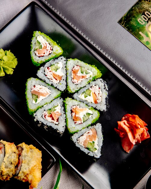 Maki con crema di salmone e granchio. cetriolo riso cetriolo zenzero wasabi vista laterale