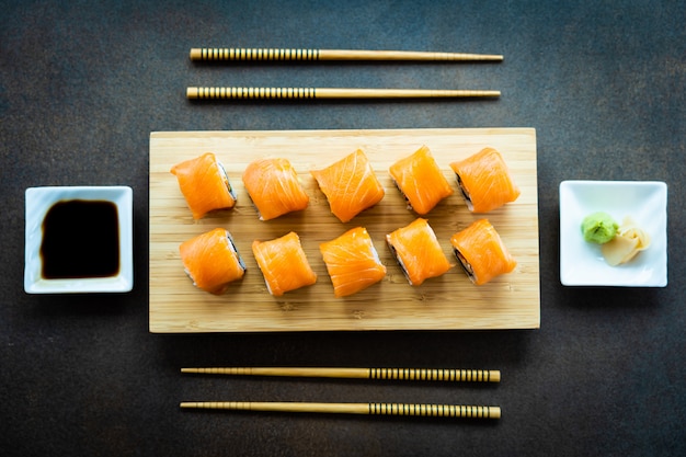 Maki del rotolo di sushi della carne di pesce del salmone sul piatto di legno