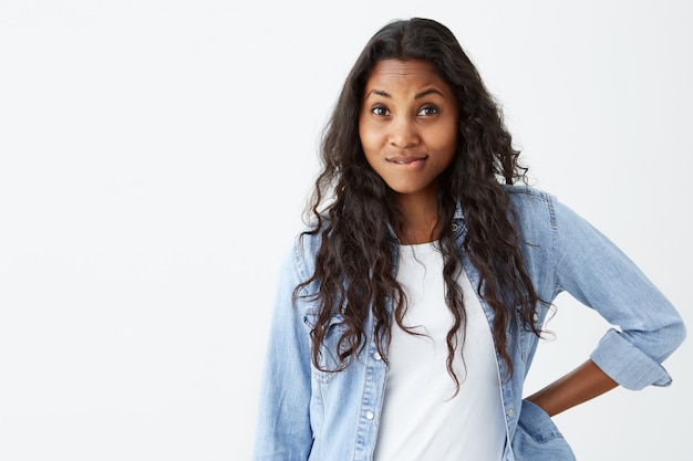 Malcontenta donna afroamericana con i capelli ondulati sciolti che curvano le labbra, con un'espressione scontrosa insoddisfatta di qualcosa. Giovane studentessa con espressione insoddisfatta.