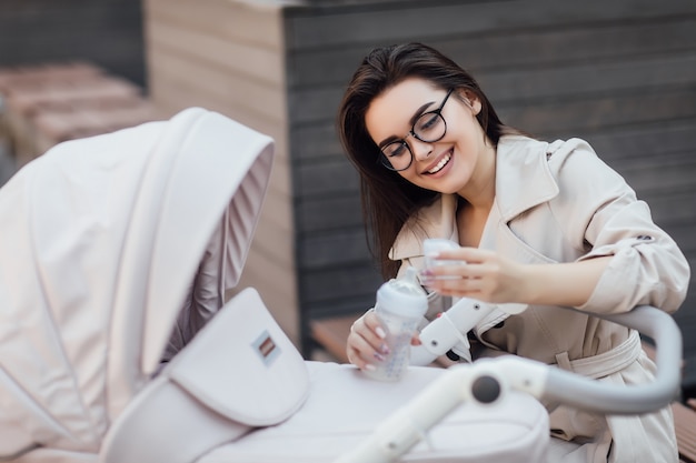 Mamma che alimenta bambino neonato con bevanda. Stile di vita sano dei bambini.