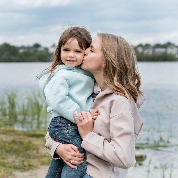 Mamma che bacia sua figlia vista frontale