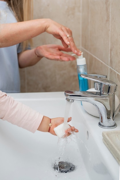 Mamma che mette il sapone sulla mano del bambino per lavarsi