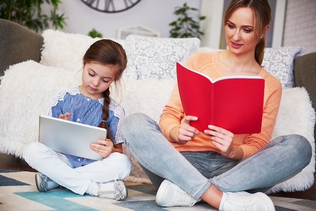 Mamma e bambino concentrati che studiano con la tecnologia