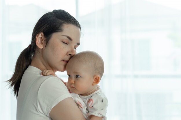 Mamma e bambino si prendono in giro felicemente su una stanza bianca