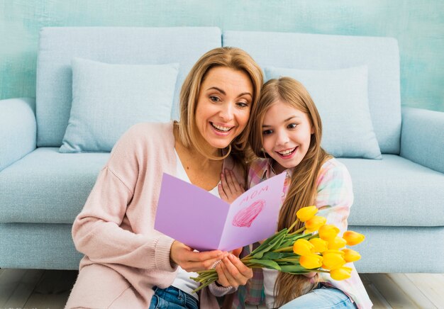 Mamma e figlia che sorridono e che leggono la cartolina del giorno del `s della madre