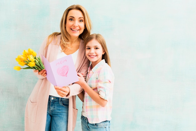 Mamma e figlia con doni sorridendo e guardando la fotocamera