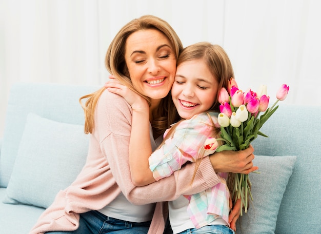 Mamma e figlia con la faccia soddisfatta che si abbracciano