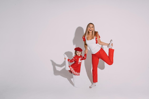 Mamma e figlia divertenti in posa su sfondo bianco.