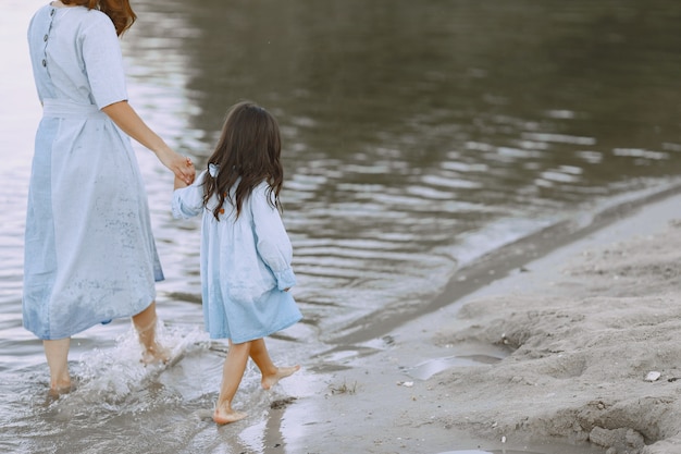 Mamma e figlia in abiti identici. Famiglia che gioca in riva al fiume.