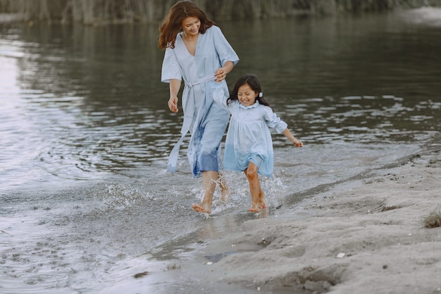 Mamma e figlia in abiti identici. Famiglia che gioca in riva al fiume.
