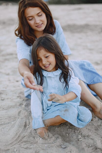 Mamma e figlia in abiti identici. Famiglia che gioca in riva al fiume.