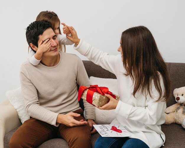 Mamma e papà con la figlia e regalo a casa