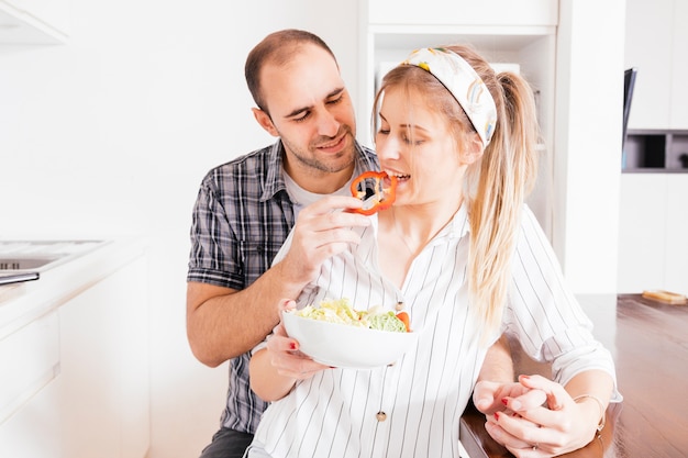 Man alimentazione insalata a sua moglie in cucina