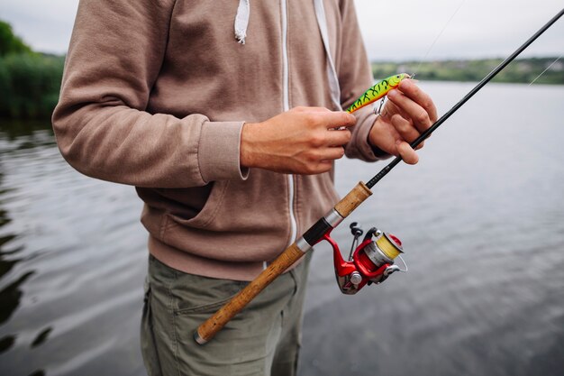 Man mano che impugna il richiamo e la canna da pesca