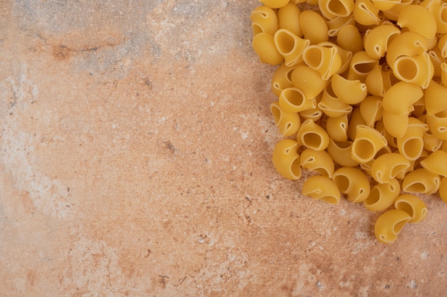 Manciata di pasta cruda non preparata su fondo di marmo. Foto di alta qualità