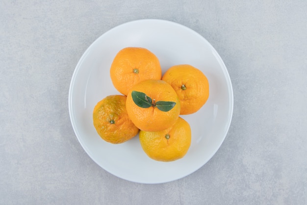 Mandarini freschi saporiti sul piatto bianco