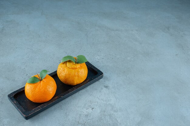 Mandarini freschi su un piatto di legno, sui precedenti di marmo. Foto di alta qualità