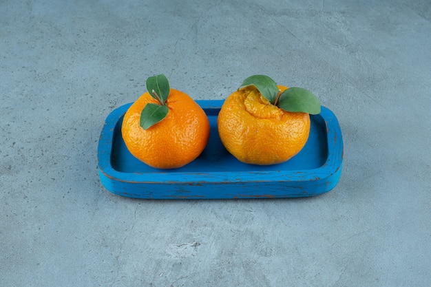Mandarini organici su un piatto di legno, sui precedenti di marmo. Foto di alta qualità