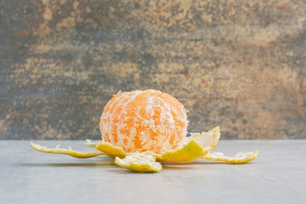 Mandarino fresco sbucciato sulla tavola di pietra. Foto di alta qualità