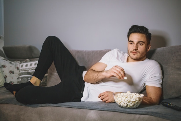 Mangia mangiando popcorn e guardando la TV