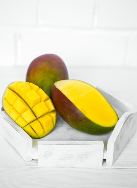 Mango aromatico maturo su fondo di legno bianco, concetto di cibo sano e frutta esotica