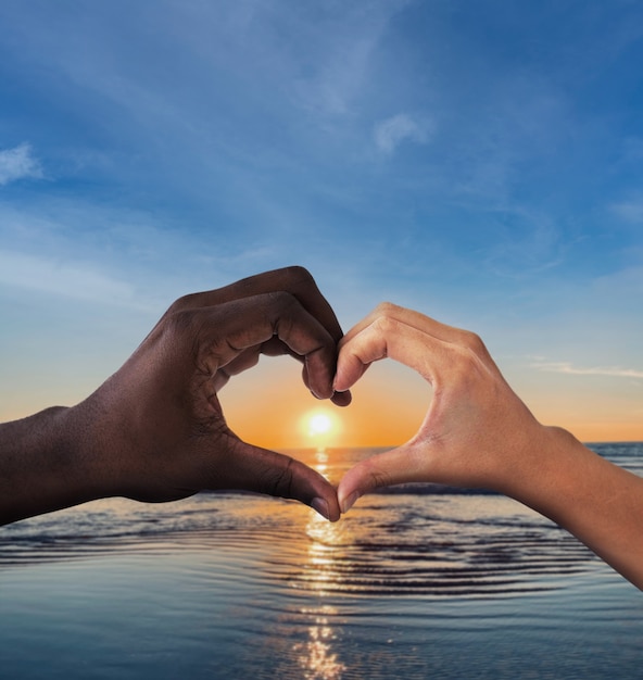 Mani a forma di cuore su un tramonto