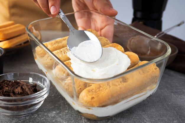 Mani ad alto angolo che cucinano tiramisù