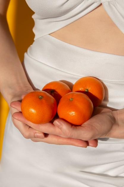 Mani ad alto angolo che tengono i mandarini